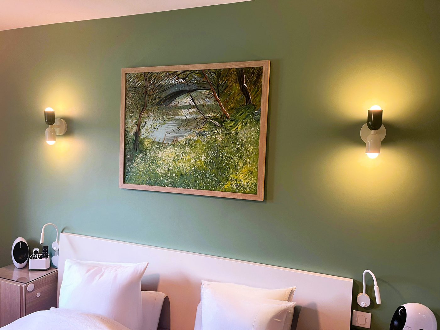 Copie d'un tableau de Van Gogh accrochée au-dessus d'un lit dans une chambre aux murs vert sauge